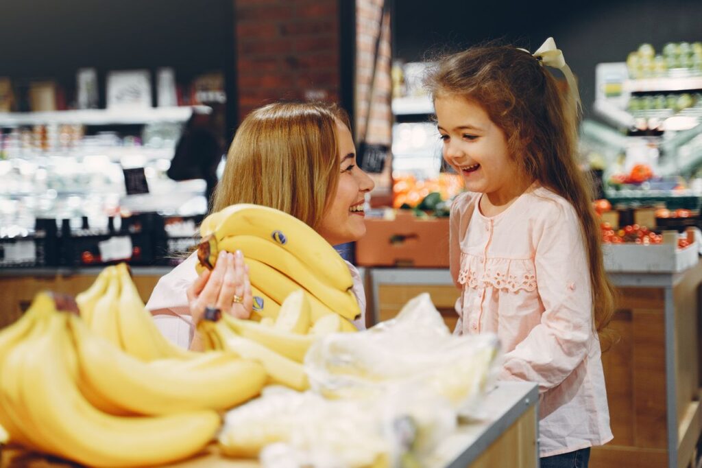 A cluster of fresh bananas showing stages of ripeness on a wooden countertop next to healthy whole foods.