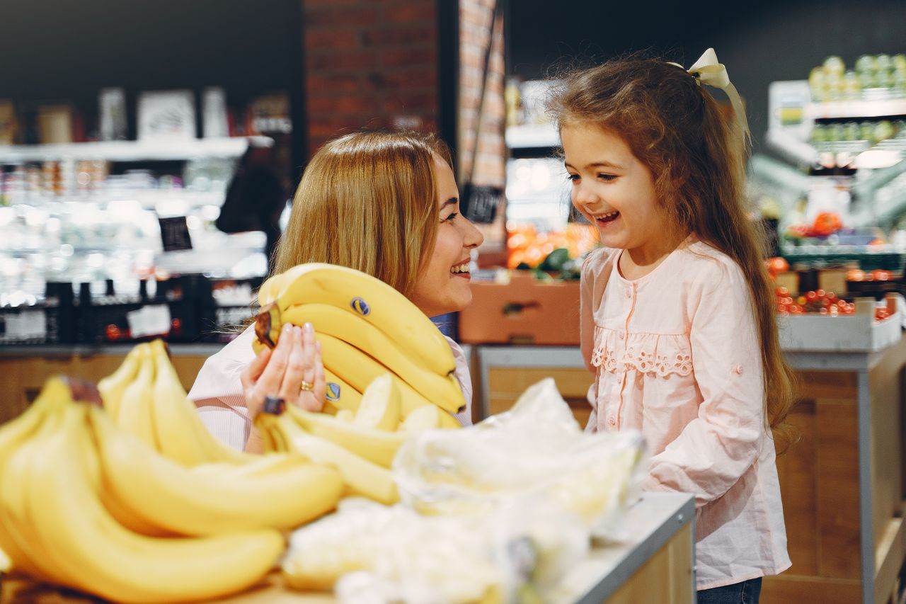 A cluster of fresh bananas showing stages of ripeness on a wooden countertop next to healthy whole foods.